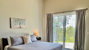 Ein Schlafzimmer mit einem großen Bett, einem Deckenventilator, einem Fenster mit Vorhängen und einem Gemälde an der Wand.