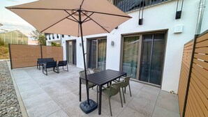 An outdoor patio with a table and chairs, a large umbrella, and a sliding glass door. - Time out in a vacation home - Small & Fine (4 guests) (Frittlingen)