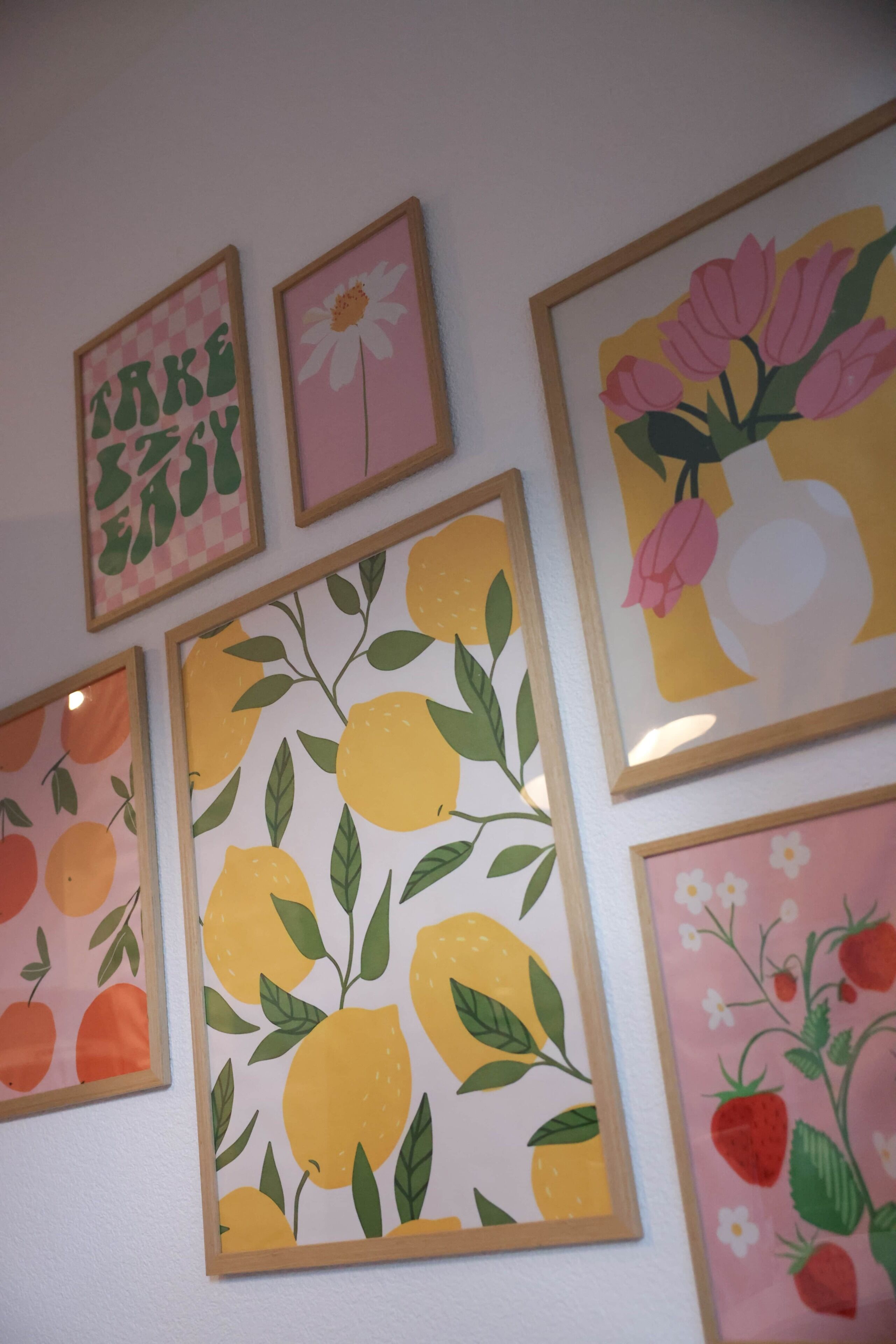 Una pared decorada con varios cuadros enmarcados, con motivos florales y frutales.