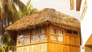 Una estructura de madera con techo de paja, un balcón y un área de estar cubierta con sillas.