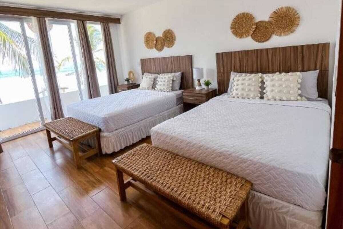 A hotel room with two beds, a large window, and a wooden floor.