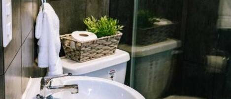 Casa de banho moderna com lavatório branco, sanita e zona de duche.
