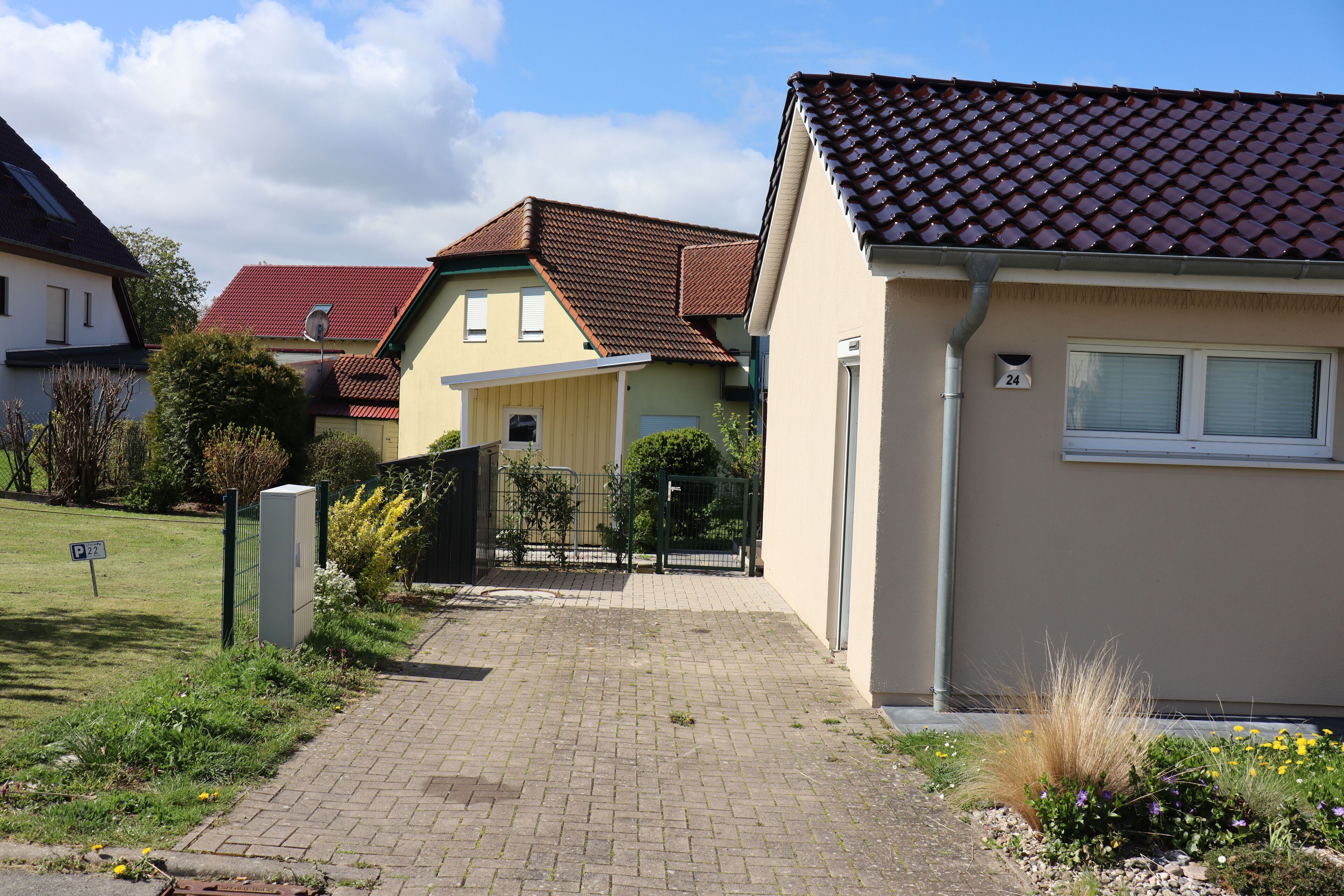 A residential area with houses, a paved driveway, and a gate.