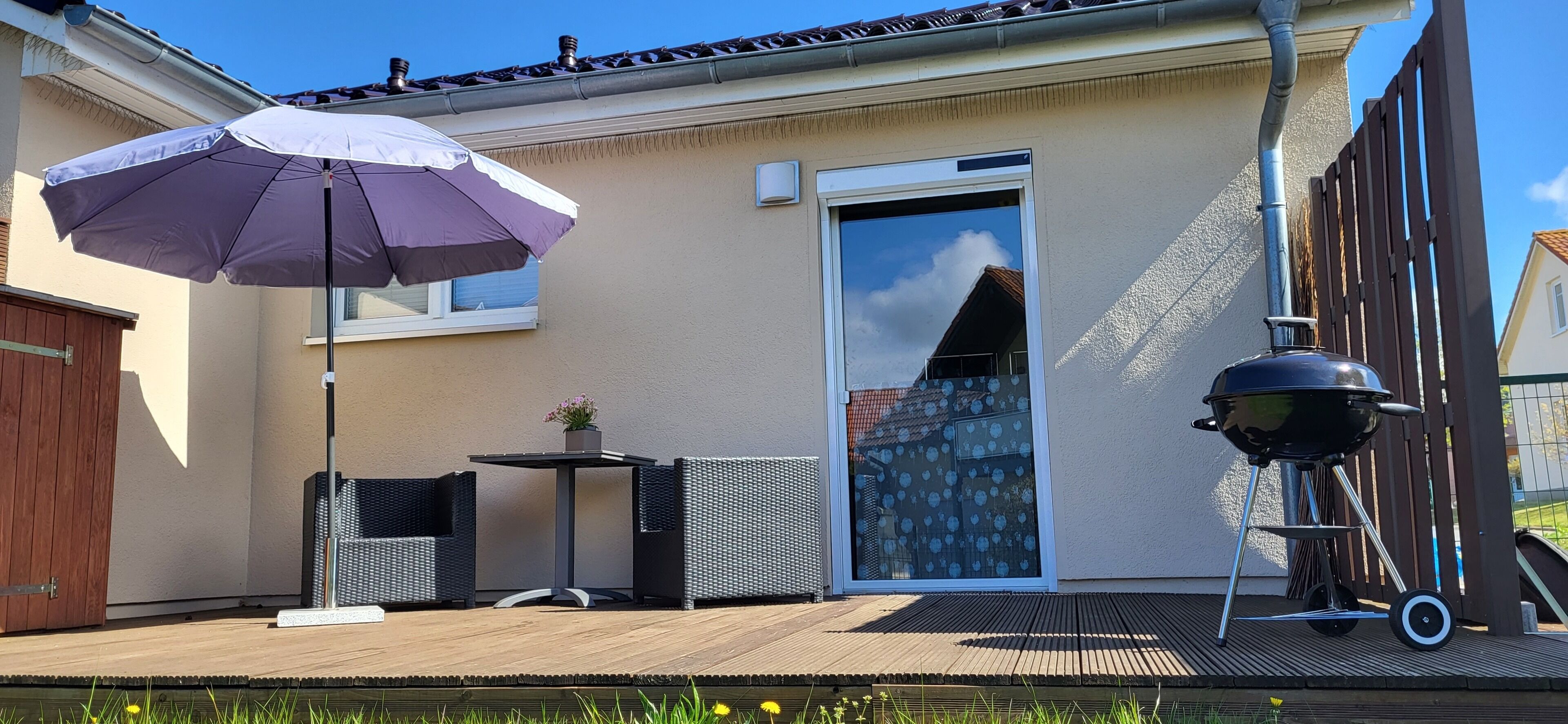 A patio with a table and chairs, a barbecue grill, and a large umbrella.
