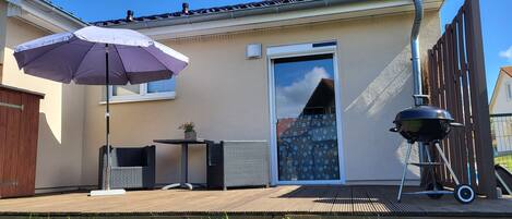 A patio with a table and chairs, a barbecue grill, and a large umbrella.