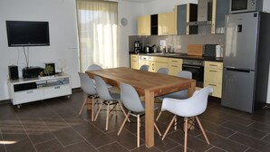 Una cocina moderna con una mesa de comedor de madera, sillas grises, horno empotrado y un refrigerador de acero inoxidable.