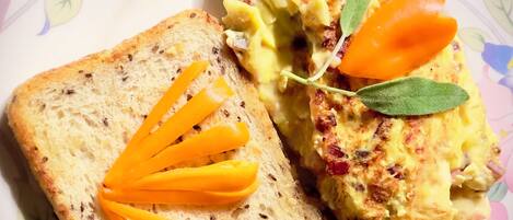A plate with a slice of bread topped with cheese and a piece of scrambled eggs garnished with a carrot and a leaf.