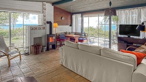 A cozy living room with a sofa, a table, and a fireplace. There is a TV and a window with a view of the outdoors.