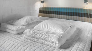 A neatly made bed with white bedding, a striped headboard, and two wall-mounted lamps.