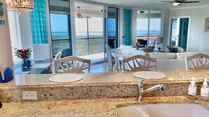 A modern kitchen with a granite countertop, a built-in dishwasher, and a large window overlooking the ocean.