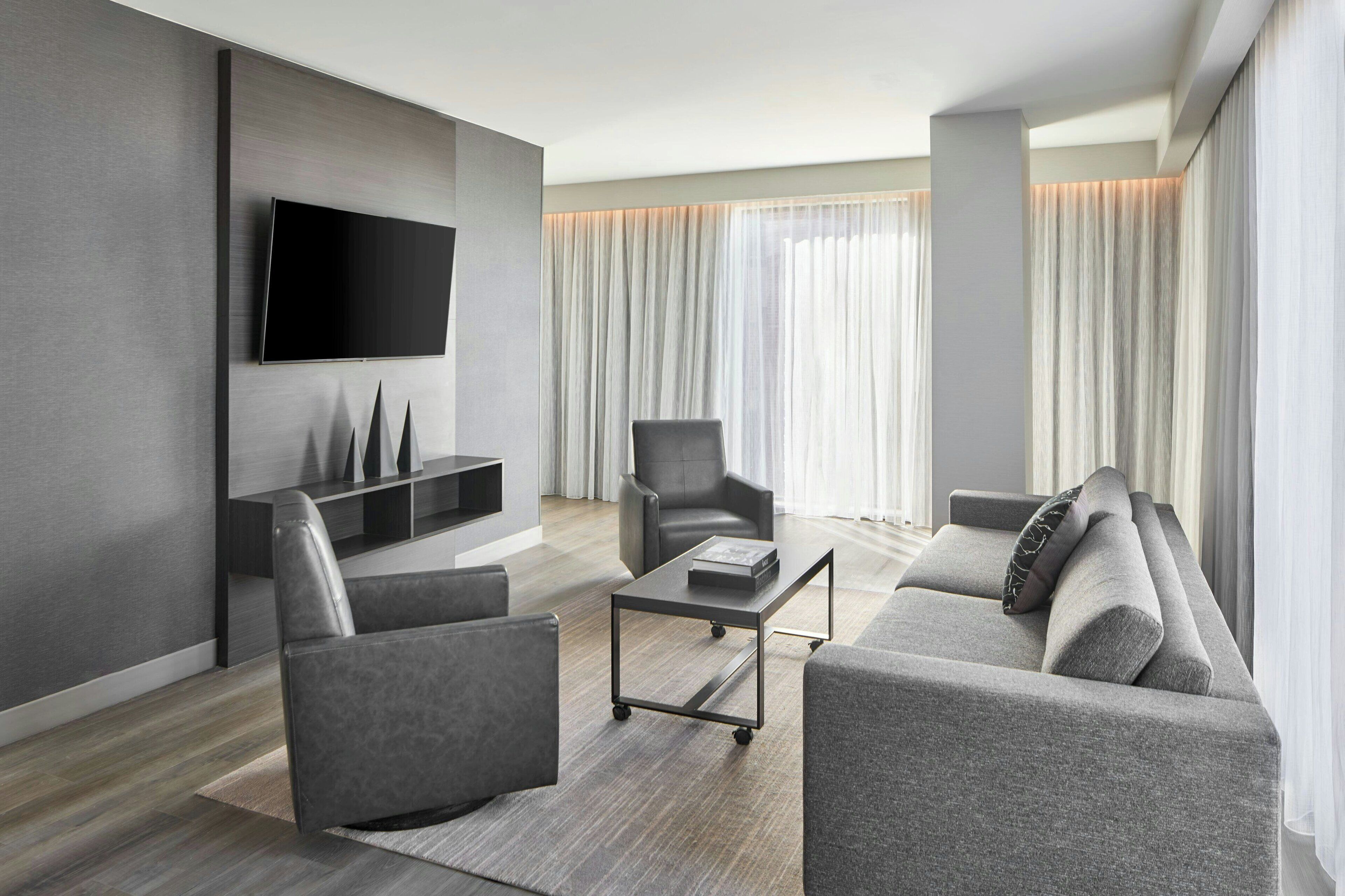 Ein modernes Wohnzimmer mit Fernseher, grauen Sofas und einem Couchtisch.