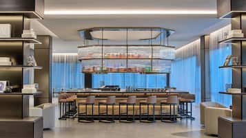 A modern bar area with a central island, bar stools, and a tiered shelving unit displaying various items.