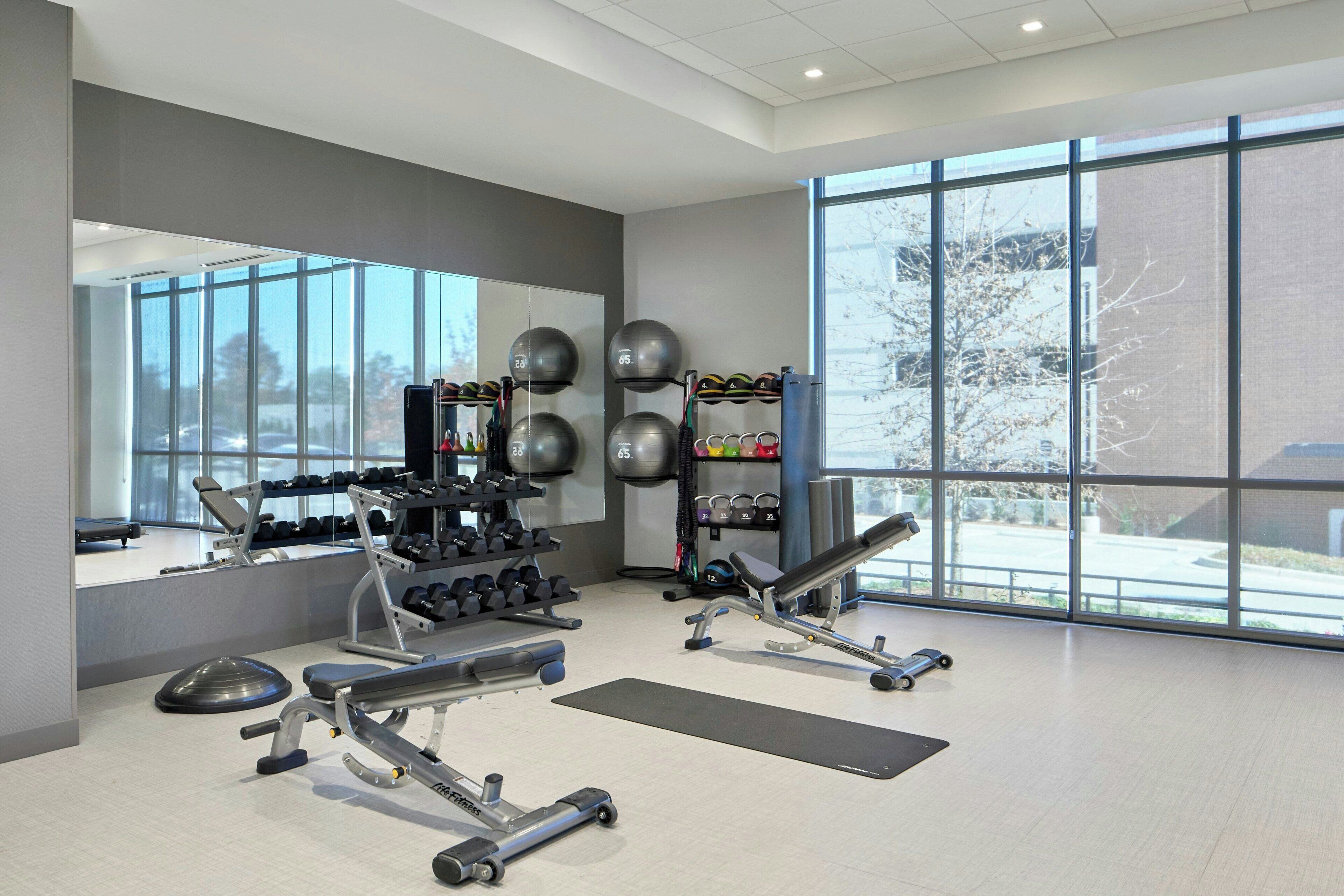 Ein modernes Fitnessstudio mit Kraftgeräten, Kurzhanteln und Trainingsbällen.