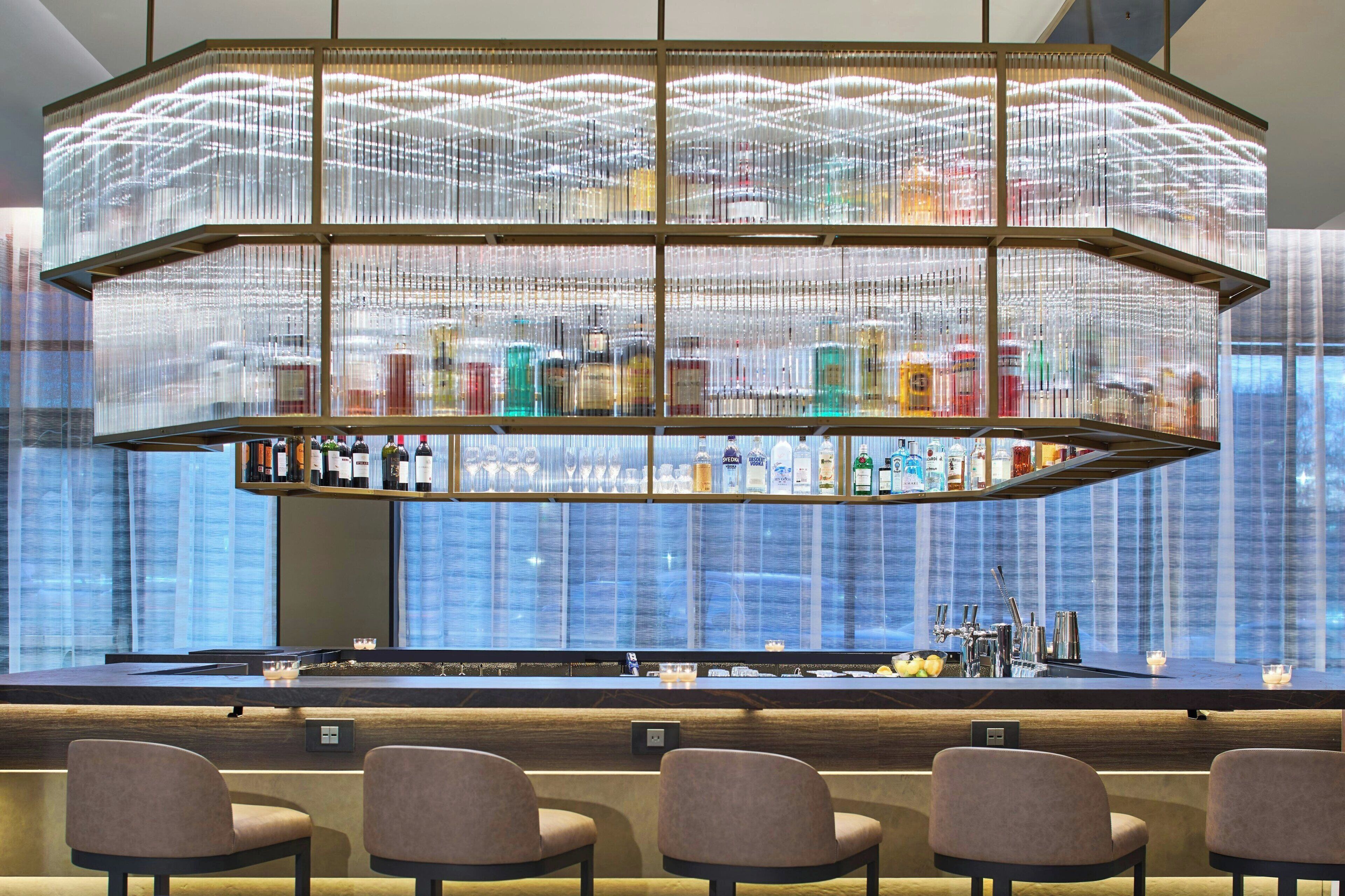 A bar area with a unique hanging light fixture and a variety of bottles displayed on shelves.