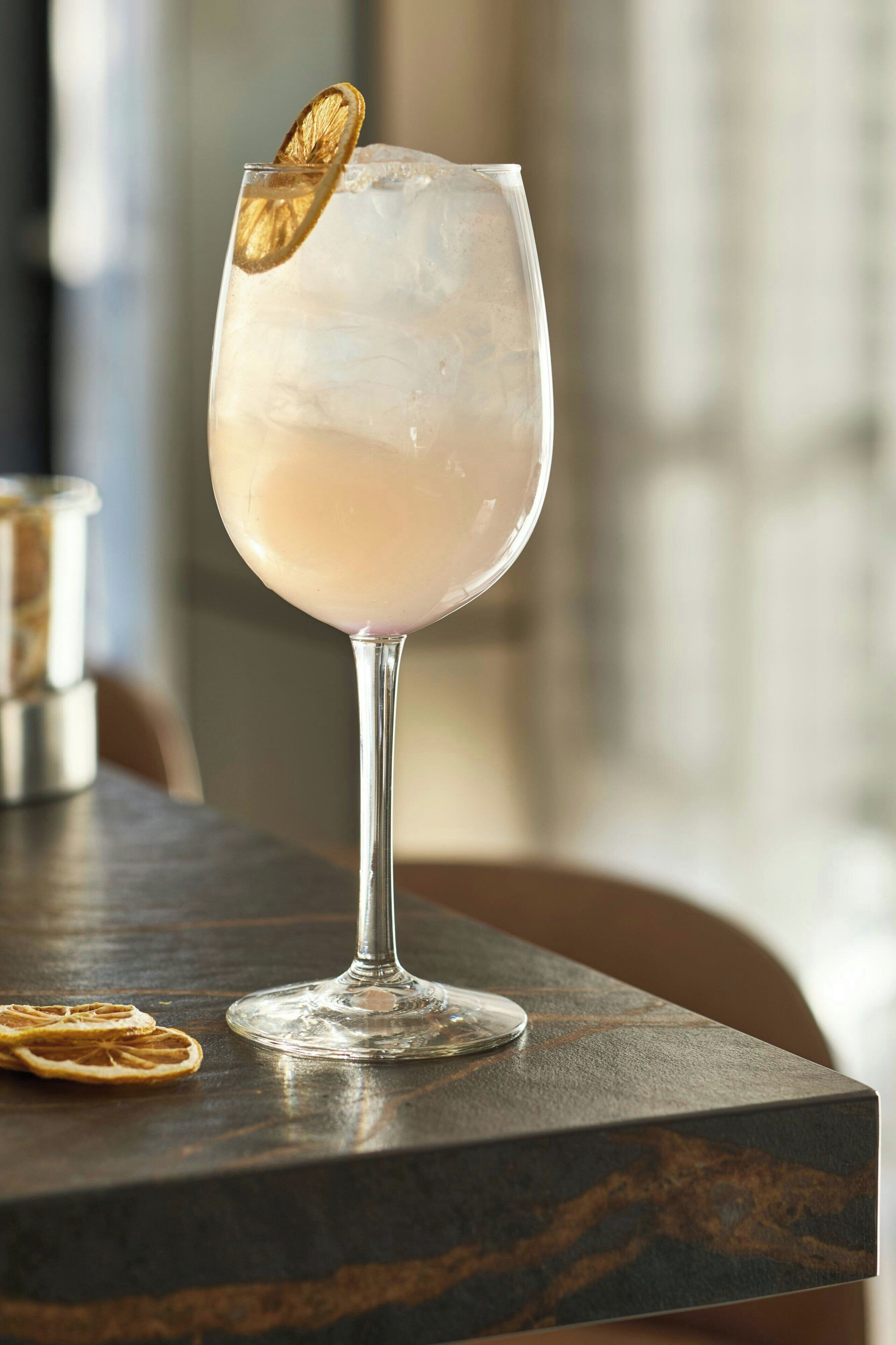 A clear glass with a lemon slice garnish on a marble table.