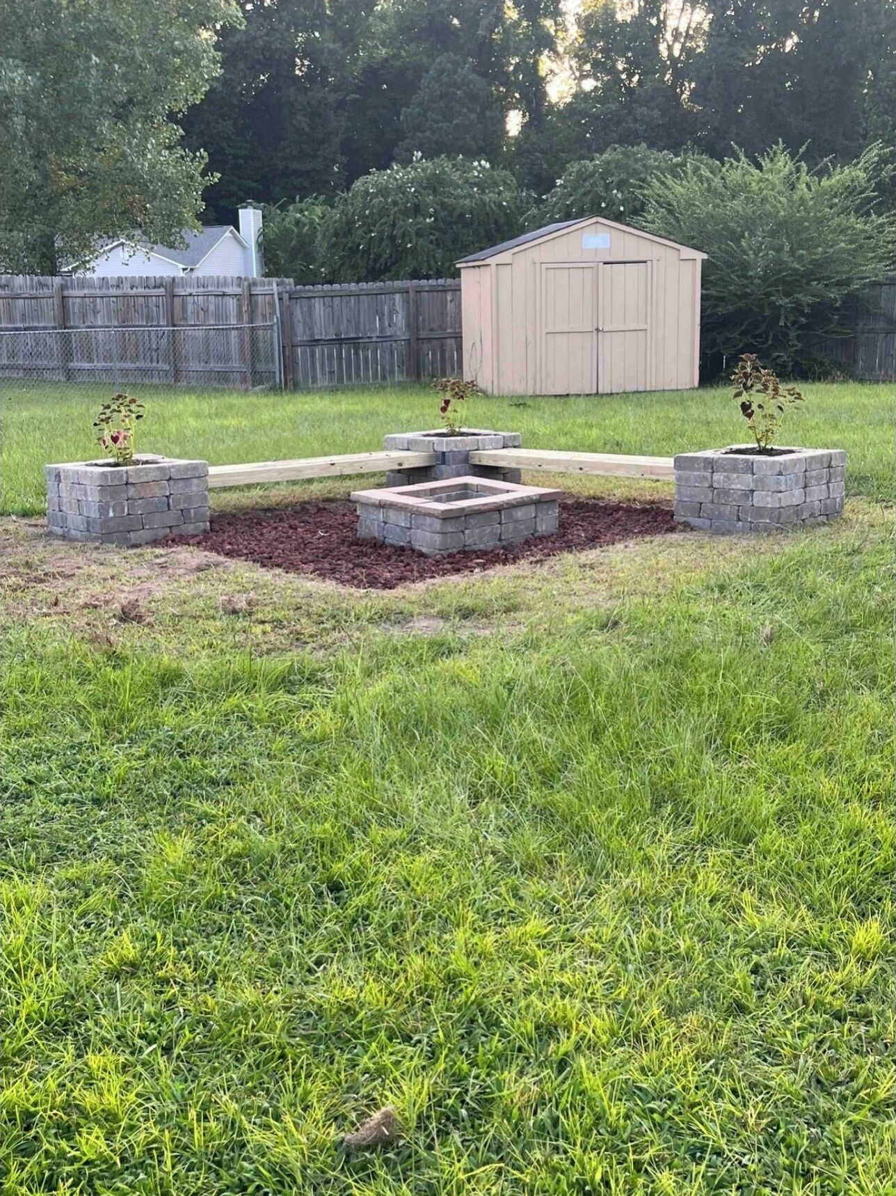 A backyard with a raised garden bed, a wooden deck, and a shed.