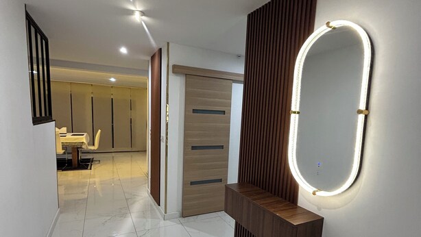 A hallway with a marble floor, a wooden vanity with a mirror, and a door with a wooden panel. - L'échapée belle (Beinheim)