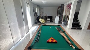 A pool table with a green felt surface, surrounded by a black and white patterned rug. - L'échapée belle (Beinheim)