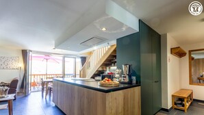 A modern kitchen with a wooden island, a coffee machine, and a dining area with chairs and a table.