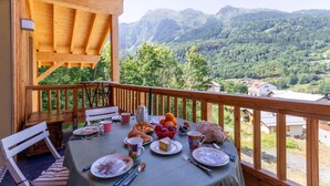 A wooden deck with a table set for breakfast overlooking a mountainous landscape.