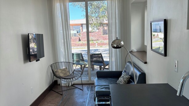 Una sala moderna con un televisor de pantalla plana, un sofá, una silla y un comedor con mesa y sillas.