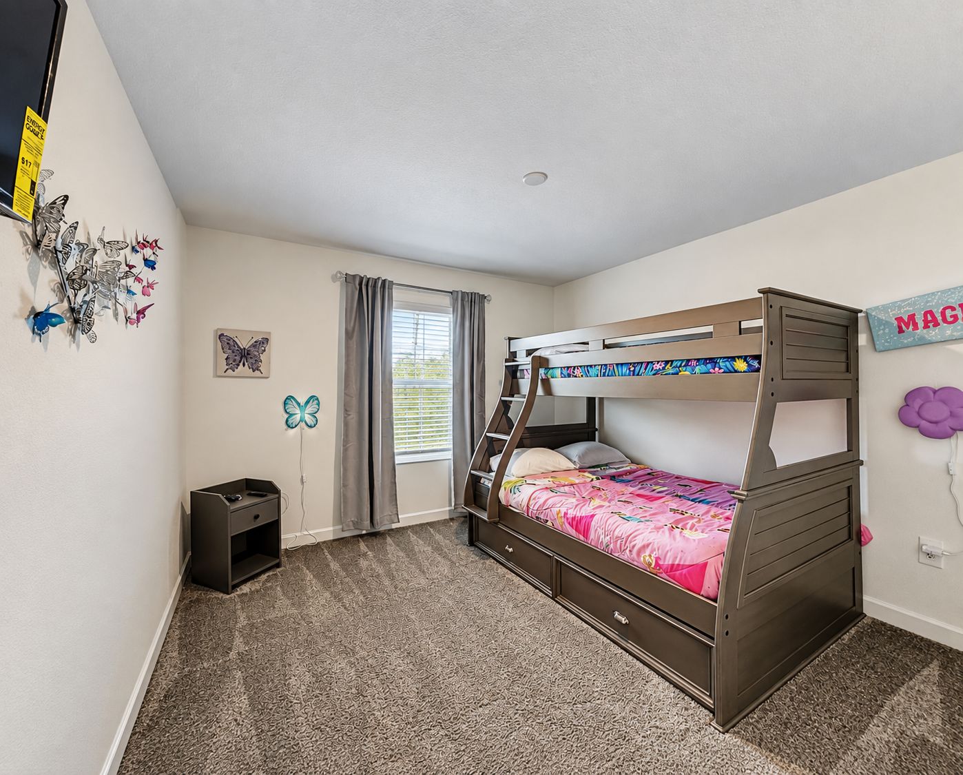 A bunk bed room with a window, a small desk, and butterfly wall art.