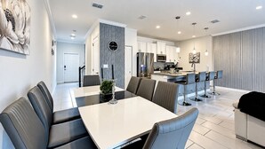 Een moderne keuken met witte kastjes, roestvrijstalen apparatuur en een centraal eiland met barkrukken.