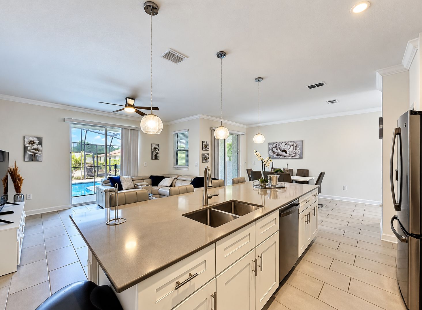 A modern kitchen with a central island, pendant lighting, and a view to a patio area.