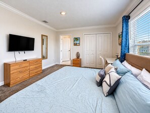 A bedroom with a large bed, a dresser, a television, and a door leading to another room. - Luxury Pool Home Near Disney Resort Access (Kissimmee)
