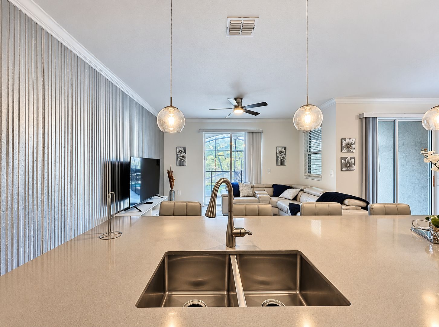 Une cuisine moderne dotée d’un îlot central, d’un évier en acier inoxydable et d’un ventilateur de plafond.