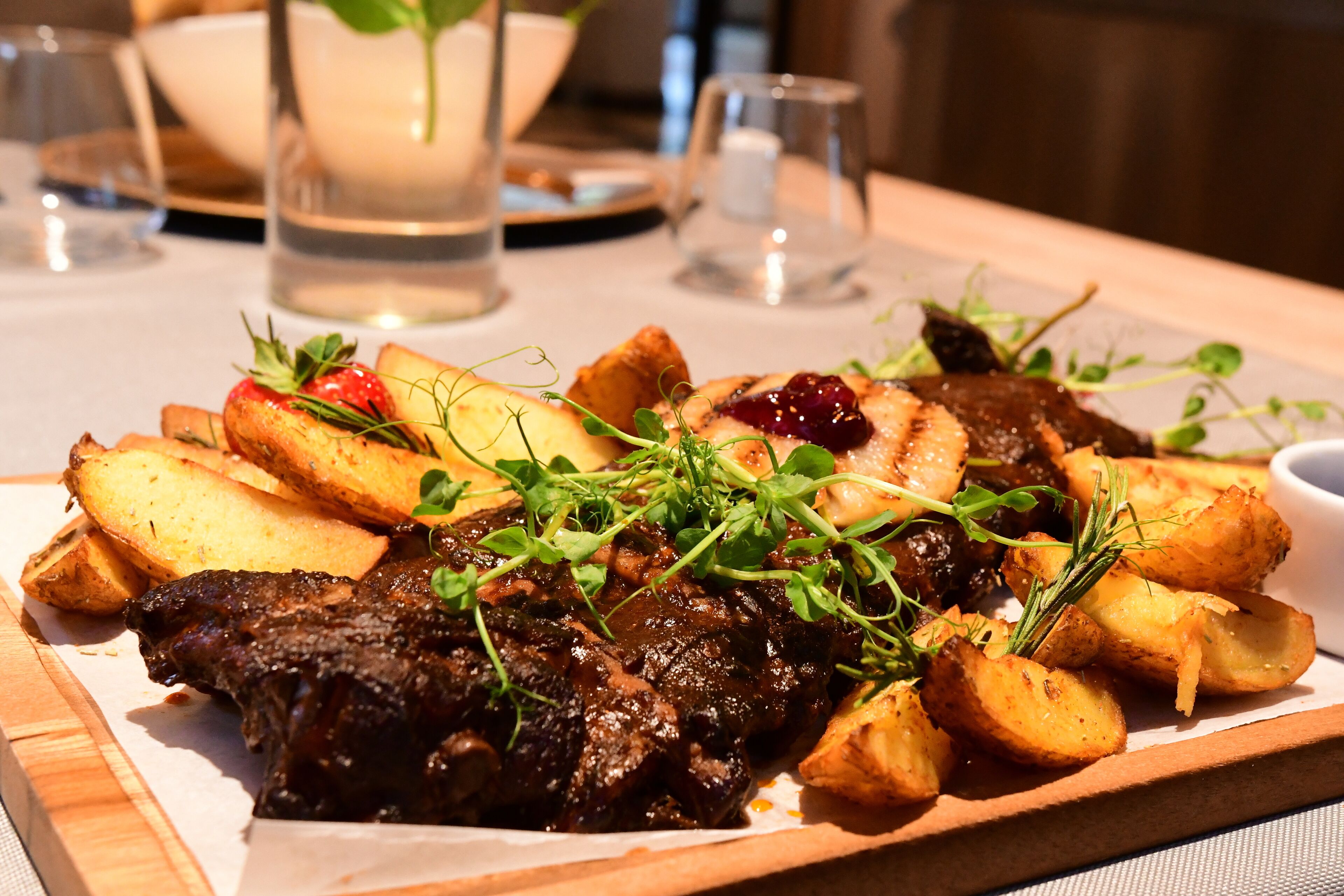 Un plato de comida con filete, papas asadas y guarniciones.