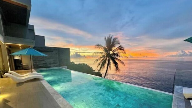 A infinity pool with a view of the ocean and a sunset.