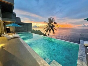 Una piscina infinita con vista al océano y al atardecer.