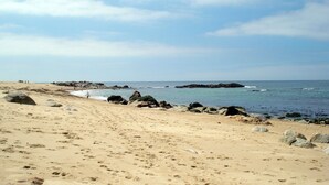 A sandy beach with large rocks and a clear view of the ocean. - Luxury Apartment on Lavadores Beach (Vila Nova de Gaia)