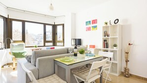 A modern living room with a glass-top dining table, a sofa, and a bookshelf. - Beautiful Views, Balcony, Downtown (Granada)