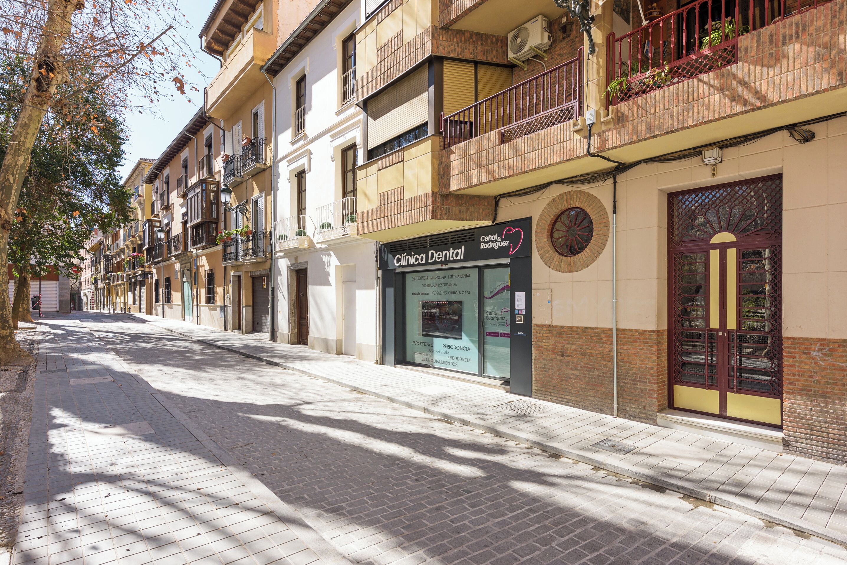 A street with a dental clinic on the corner, featuring a sign with a heart symbol and the name 'Céfalo & Rodríguez'.