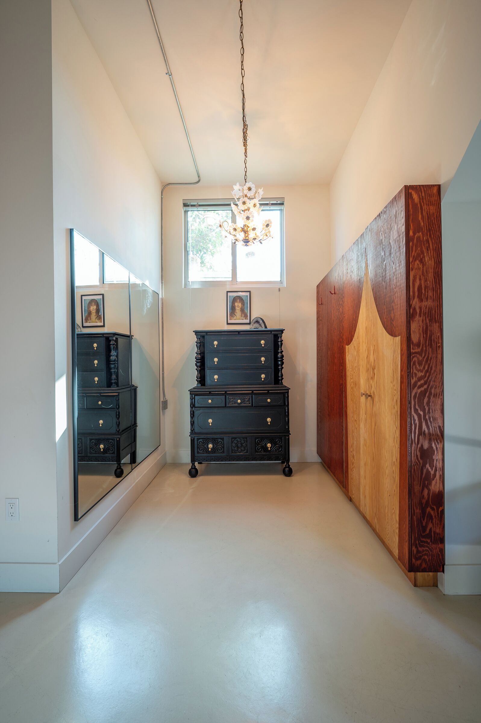 A room with a large mirror, a dresser, and a wardrobe.