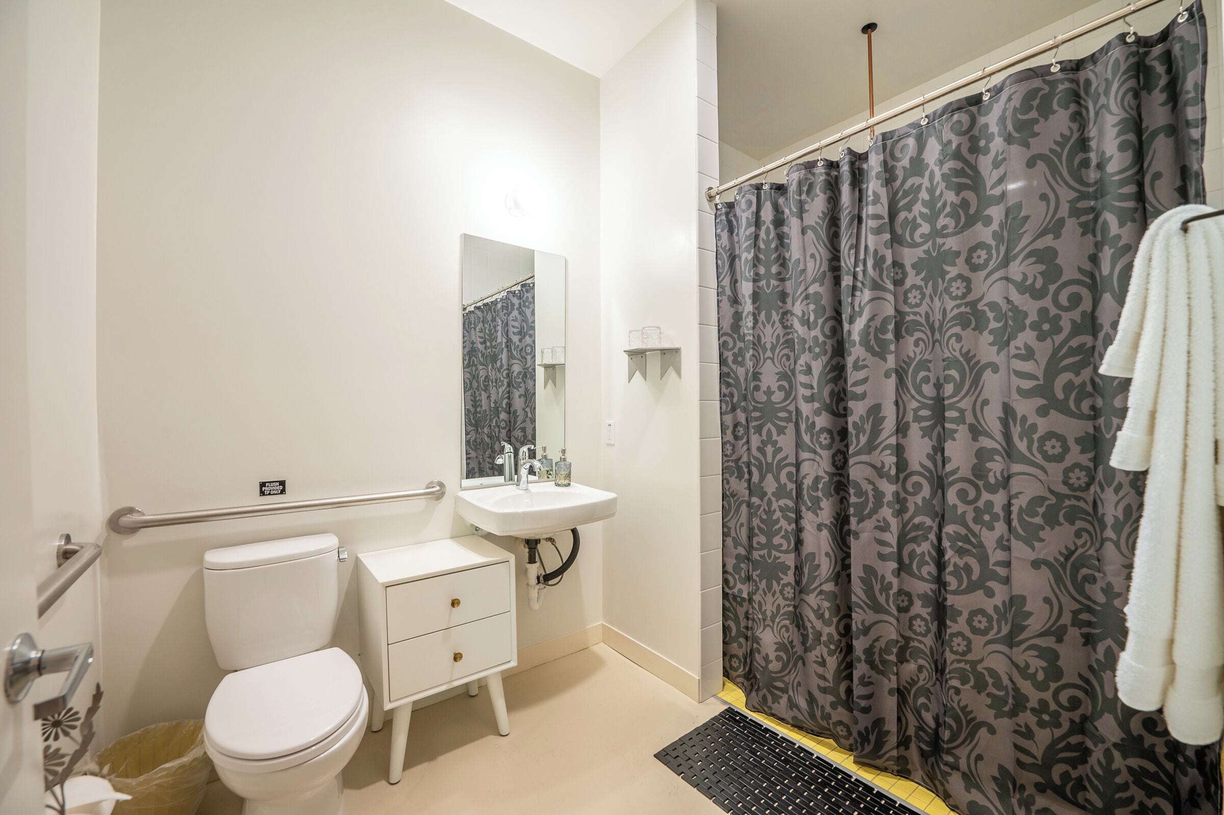 A bathroom with a toilet, sink, mirror, and shower curtain.