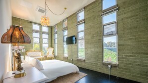 Une chambre avec un grand lit, un téléviseur fixé au mur et une vue sur la verdure.