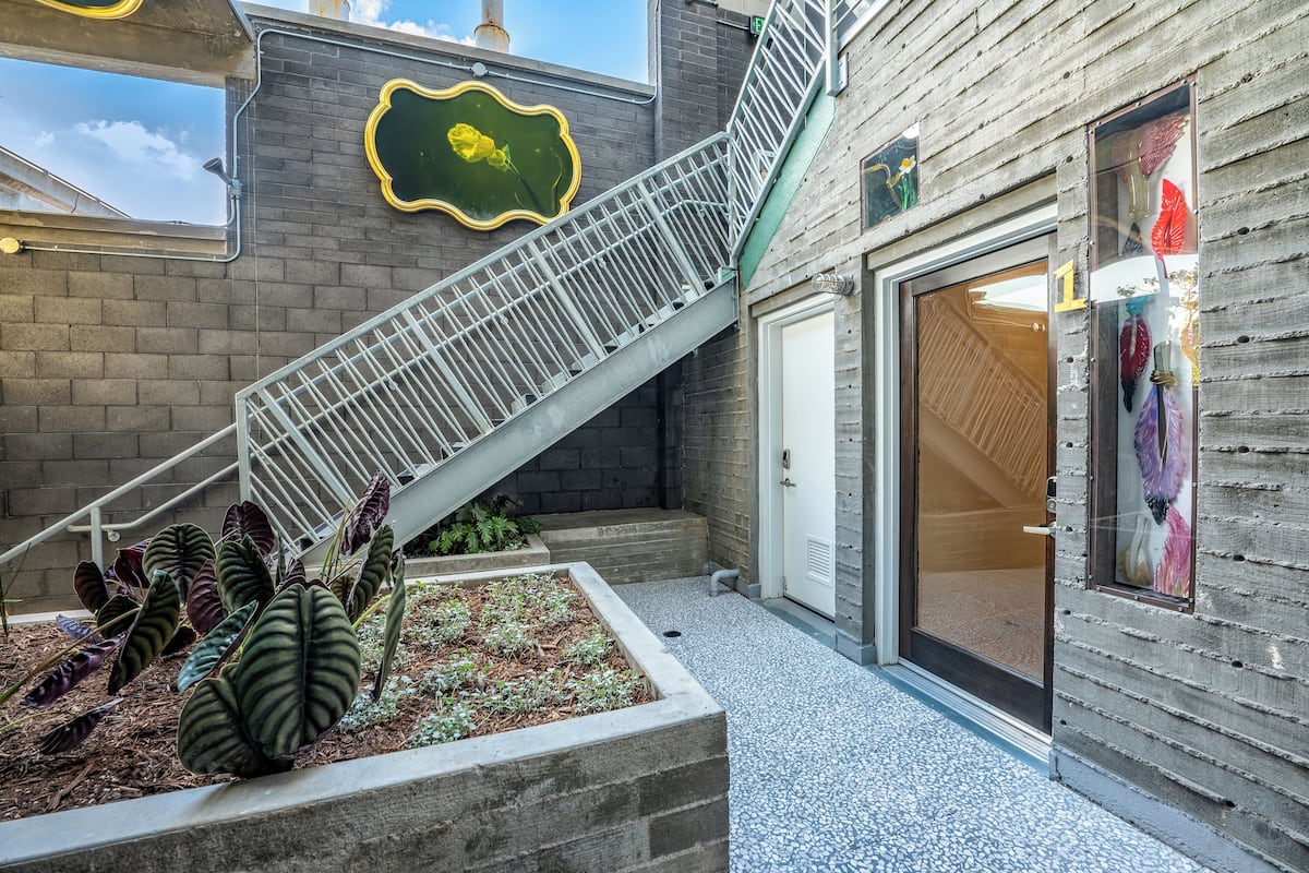 A building with a metal staircase, a door with glass panels, and a planter with plants.