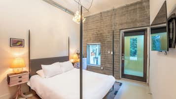 A modern bedroom with a large bed, bedside lamps, a wooden accent wall, a sliding glass door, and a mounted TV.