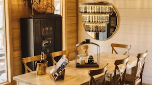 Une salle à manger en bois, avec une table, des chaises, un lustre et un buffet.