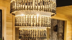 Un intérieur en bois agrémenté d’un lustre, d’une table avec une bougie et d’un bocal en verre.