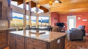 A kitchen with granite countertops, wooden cabinets, and a dining area with a view of the mountains.