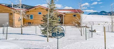 Ein Chalet mit Holzfassade, einem umzäunten Garten und einem Schild mit dem Namen des Hauses.