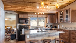A kitchen with wooden cabinets, a granite countertop, and a central island with stools.