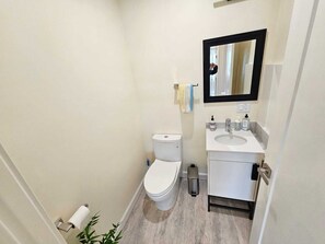 Un baño pequeño con inodoro, lavamanos y espejo.