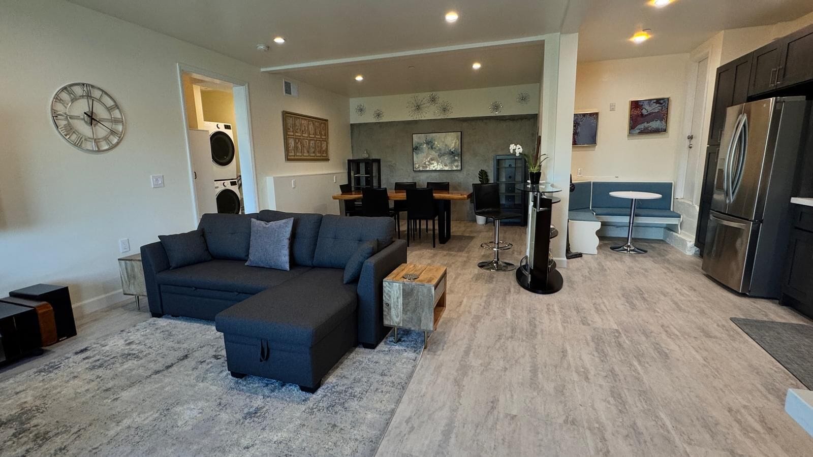 A modern living room with a sectional sofa, a coffee table, and a dining area with a table and chairs.