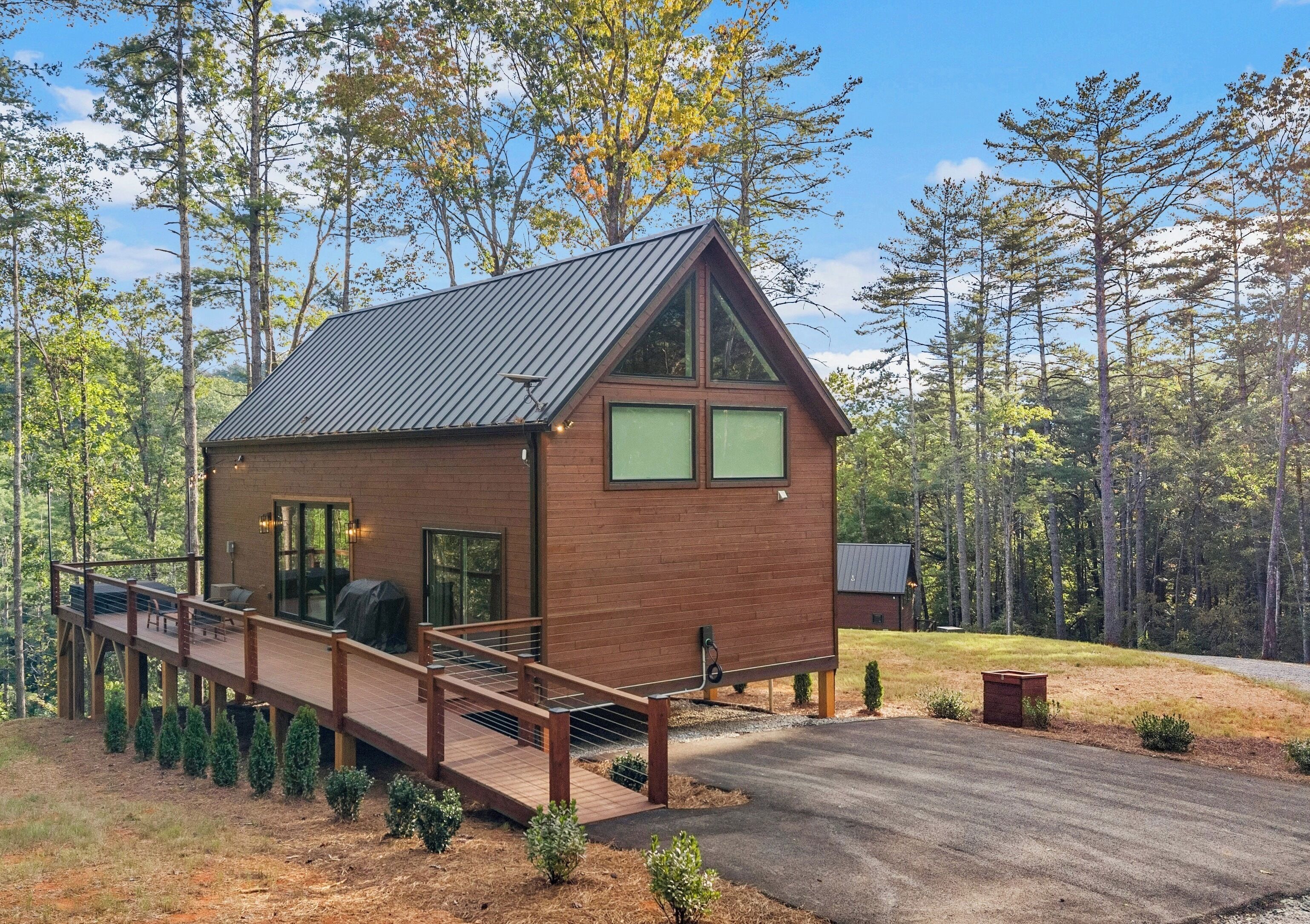 A modern cabin with a wooden exterior, large windows, and a deck.