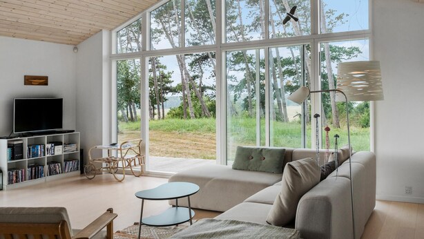 A spacious living room with a large window, a sofa, a TV, and a bookshelf. - Amazing home in Nykøbing Sj with WiFi (Nykøbing Sj)